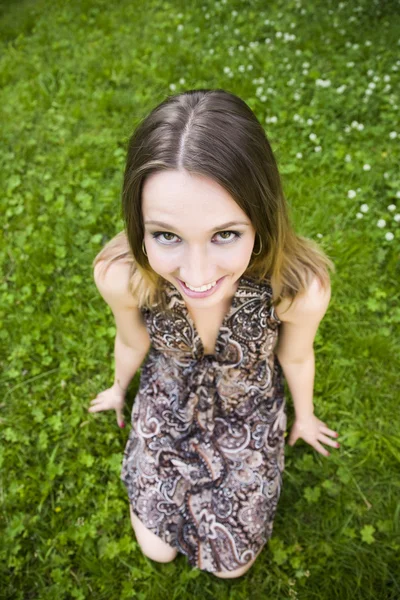Ung kvinde sidder på græs - Stock-foto