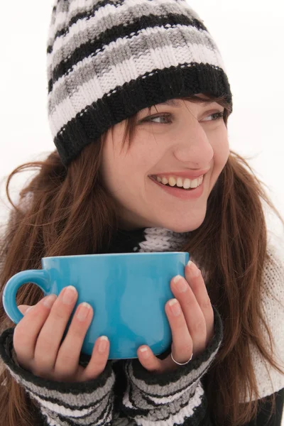 一个年轻的女子 在条带化的帽子和手套 微笑着和持有蓝杯 — 图库照片