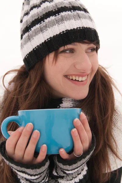 stock image A young woman in a striped hat and gloves, smiling and holding a blue cup