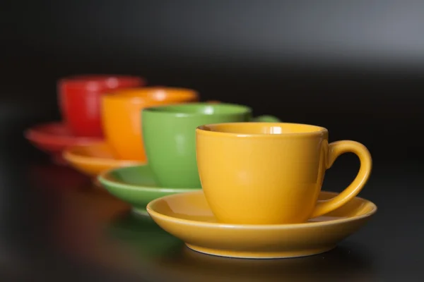 Vier farbige Tassen auf schwarzem Hintergrund — Stockfoto