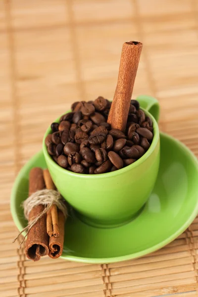 Koffiebonen en kaneel stok in een groene kopje — Stockfoto
