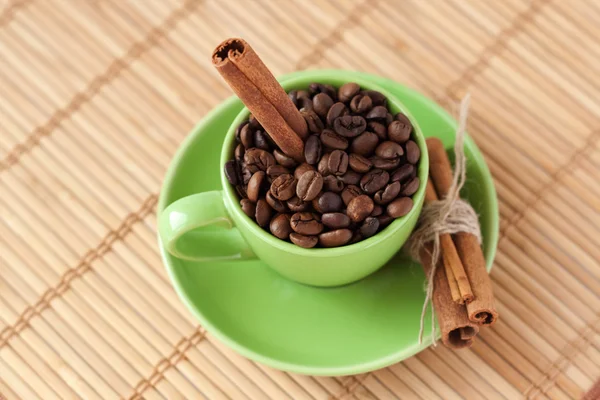 Koffiebonen en kaneel stok in een groene kopje — Stockfoto