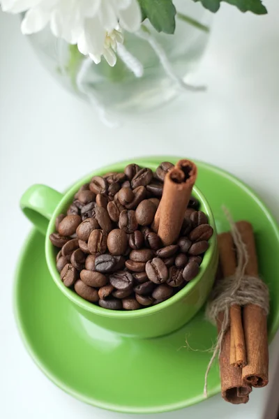 Κόκκους Καφέ Ένα Πράσινο Κύπελλο Και Ξυλάκια Κανέλας — Φωτογραφία Αρχείου