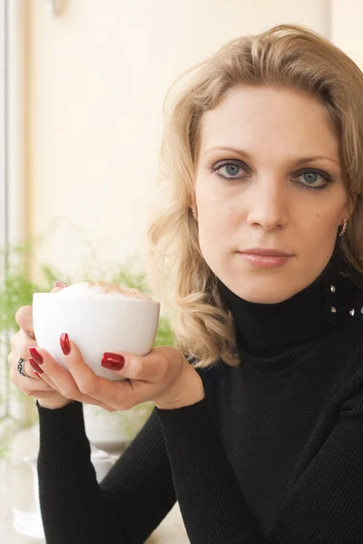 Porträtt av en ung blond skönhet med en kopp cappuccino — Stockfoto
