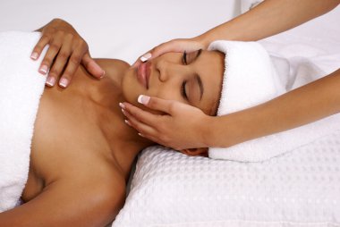 Beautiful young female relaxes during her spa facial treatment. clipart