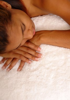 Young female dozes off for a nap on plush white carpet. clipart