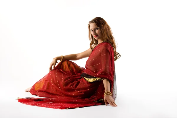 Junge Frau in traditioneller Tracht sitzt auf weiß — Stockfoto