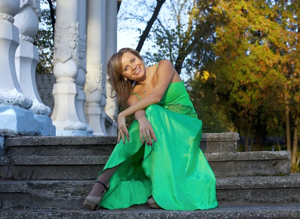 Piękna kobieta w zielonym ubraniu siedzieć na schodach — Zdjęcie stockowe