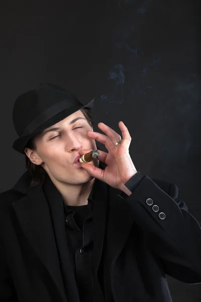 Mann in schwarzem Tuch und Hut raucht Zigarre — Stockfoto