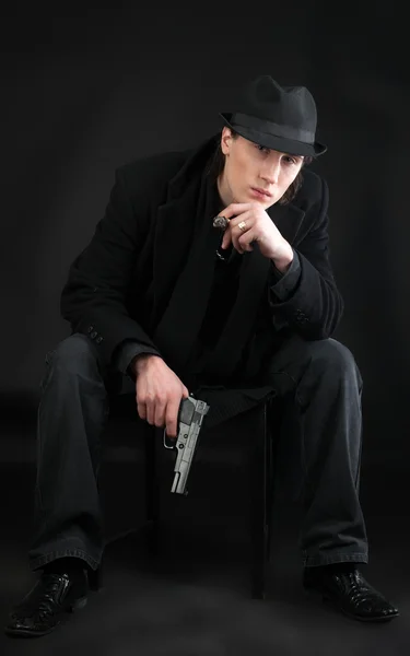 Adam tabancayla oturup siyah kumaş — Stok fotoğraf