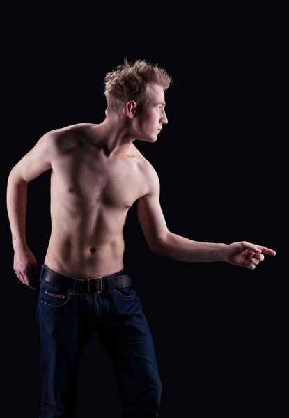 Молодой голый мужчина в джинсах позирует на черном — стоковое фото