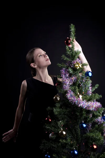 Mladá žena zdobí vánoční strom — Stock fotografie