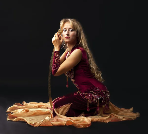 Mujer de belleza en traje árabe sentarse con sable — Foto de Stock