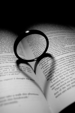 A lens filter standin up ontop of a book casting a shadow of a heart. Black and white image. clipart