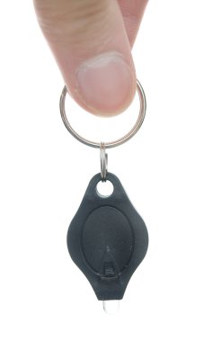 Miniature LED keychain light isolated on white with a hand holding it clipart