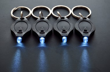 Miniature LED keychain lights on a black surface with shallow depth of field. clipart