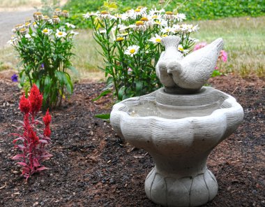 A cement birdbath in a garden clipart