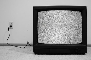 An old CRT TV plugged into the wall with static on the screen. clipart