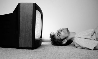 An old CRT TV plugged into the wall with static on the screen with a man watching it closely. clipart