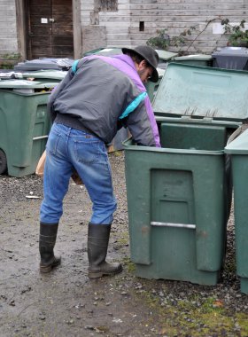 Man carefully placing glass bottle in recycle bin. This can also be used for a trash bin concept clipart