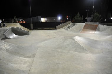 Empty skatepark at night with grind rails. Concrete cement. clipart