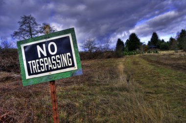 NO TRESPASSING sign in front grass rural country driveway field clipart