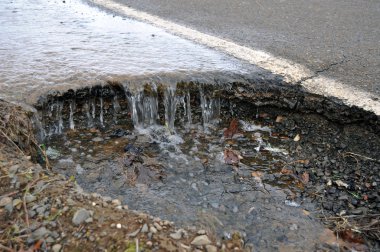 Flood of Water corroding asphalt street road. A natural disaster. clipart