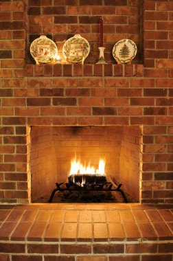 Simple clean brick fireplace with a single fire log burning out to give heat. There are Christmas plates decorating it at the top, but those can be cropped out clipart