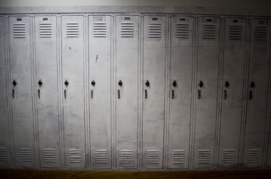 A row of poorly painted white lockers with shadows covering the sides of them. The lockers look old and worn down. clipart