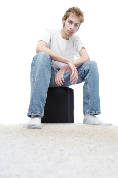 Jonge man zit op een subwoofer Luidsprekerbox — Stockfoto