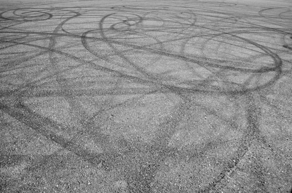 A bunch of random skid marks from cars in an empty asphalt parking lot. Lots of random ones.