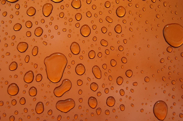 オレンジ色の光沢のある表面に大規模な雨の滴 — ストック写真