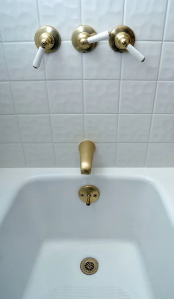 stock image New golden bathtub valves on white tile