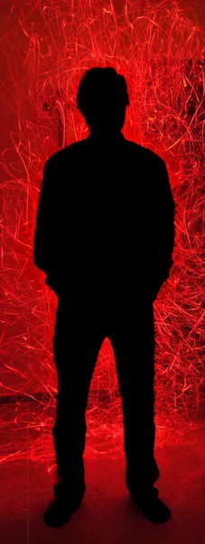 Silhueta homem atrás de fogo vermelho faíscas inferno — Fotografia de Stock