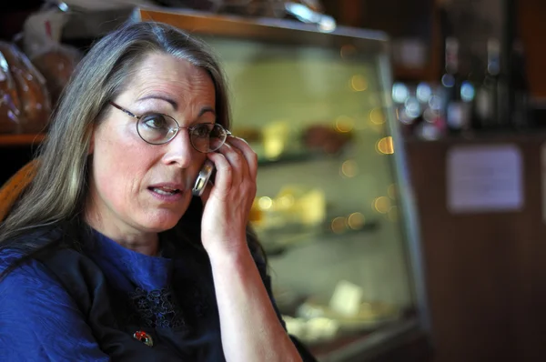 Midden leeftijd vrouw praten op mobiele telefoon binnen een winkel — Stockfoto