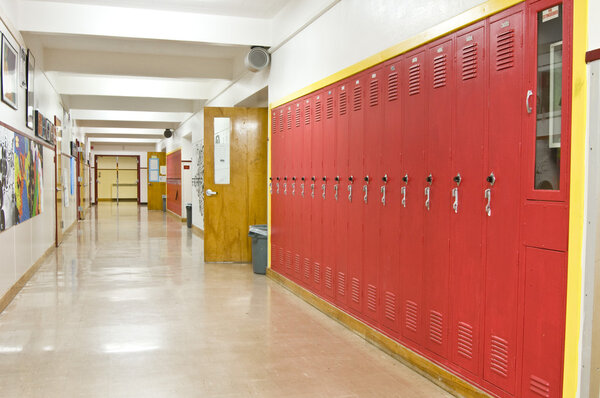 Пустой школьный коридор с красными шкафчиками на правой стороне
