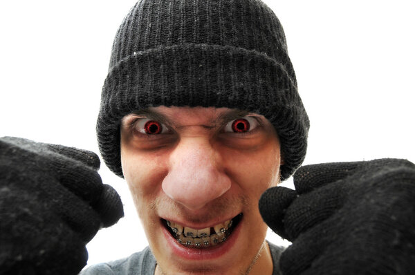 Молодой грабитель-бандит в черной шапочке и черных перчатках, изолированный на белом фоне, держит кулаки к камере. У него красный цвет
