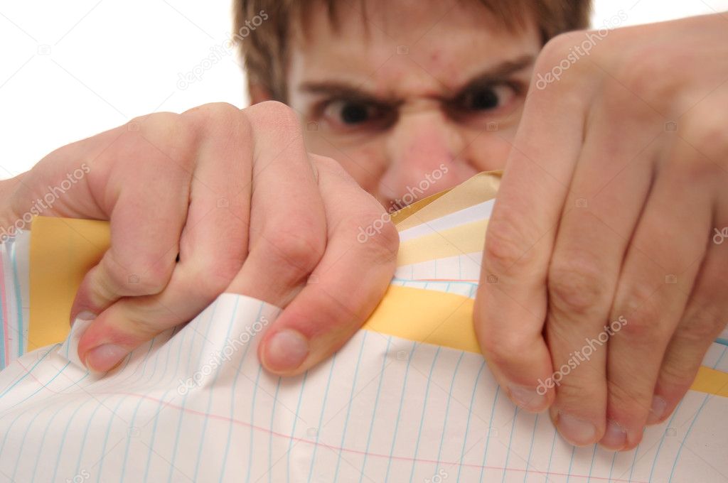 Angry young man ripping trying to papers on white background. Background is blurred intentionally.