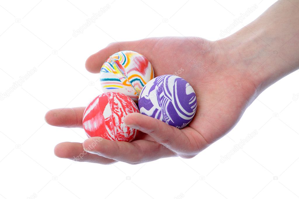 Hand holding a set of round bouncy rubber balls with colorful designs on them