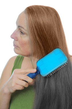 Woman combs her hair gray to brown showing the signs of old age and youth clipart