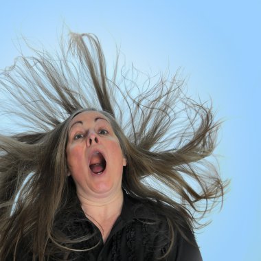 A woman screaming in front of a blue background with her hair blasting behind her. clipart