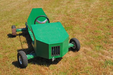 A green soapbox racing car displayed on the grass. clipart