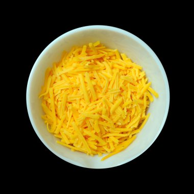 An aerial view of a white bowl containing yellow cheddar cheese isolated on a pitch black background. clipart