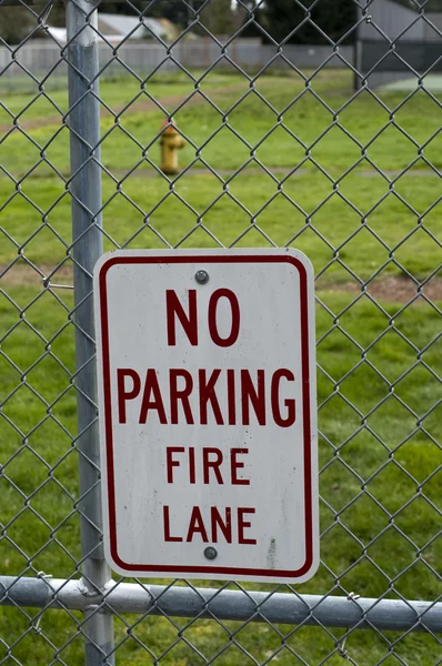 在与消火栓在篱笆后面说 没有停车火巷 的栅栏上的标志 — 图库照片