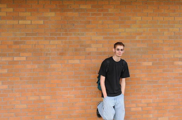Student před cihlová zeď — Stock fotografie