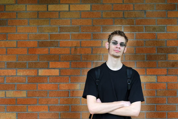 Студент, що спирається на цегляну стіну — стокове фото