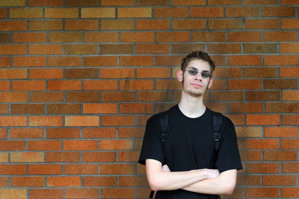Estudiante apoyado contra la pared de ladrillo — Foto de Stock