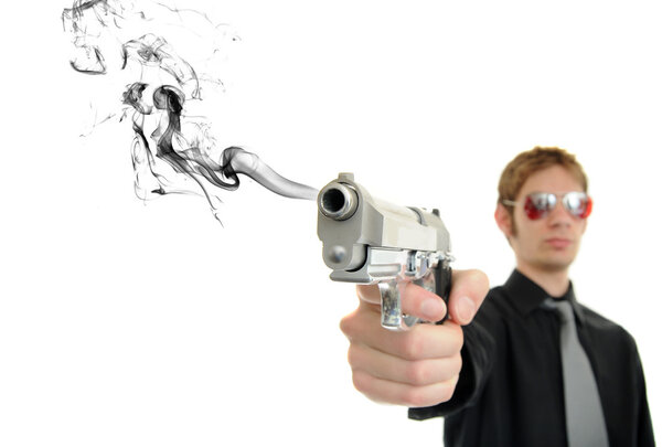 Young man holds his pistol out and shoots out smoke