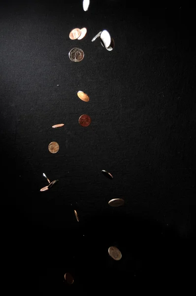 Münzen fallen in die Dunkelheit — Stockfoto