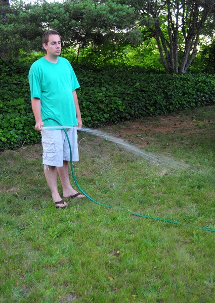 人の若い白人男性 ホースを保持し 彼の草の庭の水 — ストック写真
